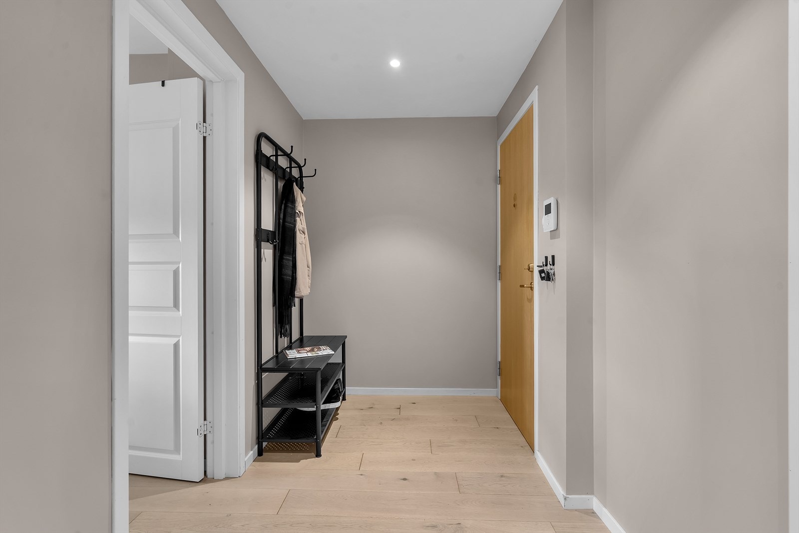 Velkommen inn i en lys og innbydende entré som setter standarden for resten av boligen. Taktspotter gir et moderne og stilrent preg, samtidig som de sørger for rikelig med lys. Ved inngangsdøren finner du et brukervennlig callinganlegg med lyd og bilde. Galleribilde