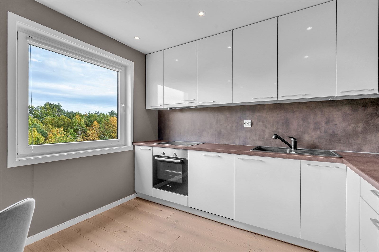 De moderne, slette frontene og de integrerte hvitevarene - inkludert platetopp, komfyr og oppvaskmaskin - gir et helhetlig og elegant preg. Galleribilde