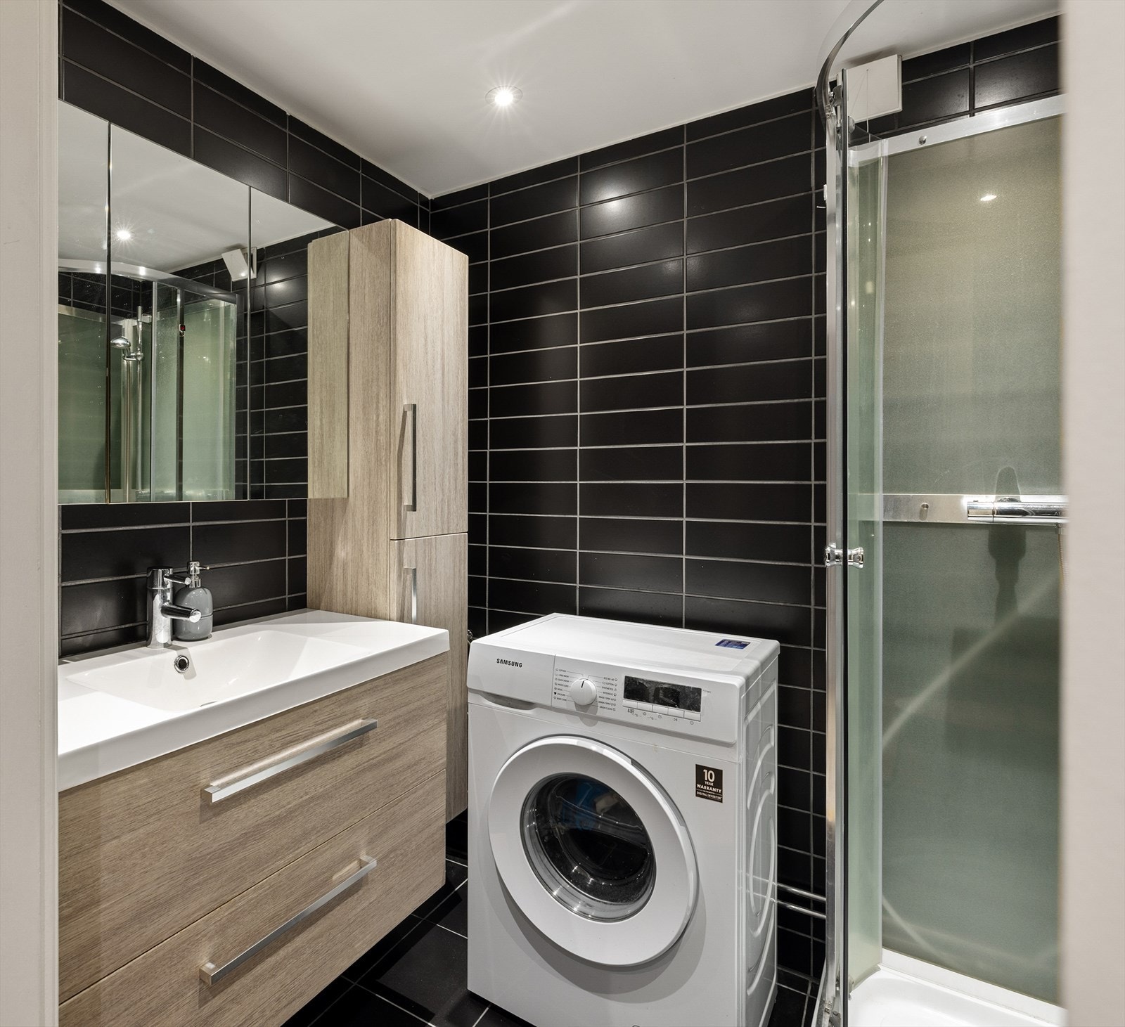 Flislagt bad med opplegg for vaskemaskin og praktiske oppbevaringsløsninger. Galleribilde