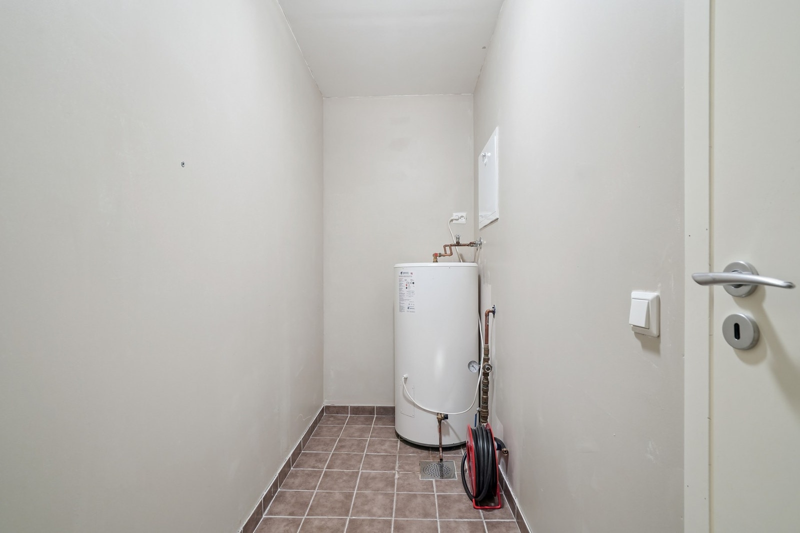 Varmtvannstank og brannslange plassert i bod. Sluk i gulvet. Galleribilde