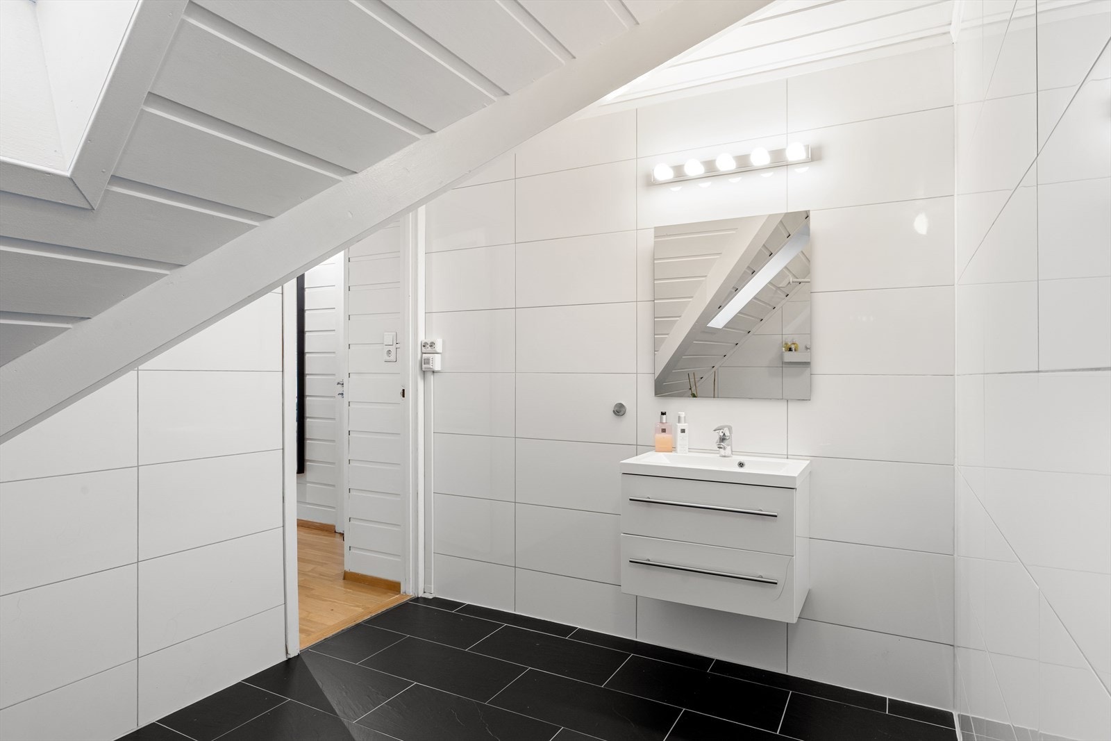 Pent bad med fliser på gulv og vegg, badekar, wc og vask. Galleribilde