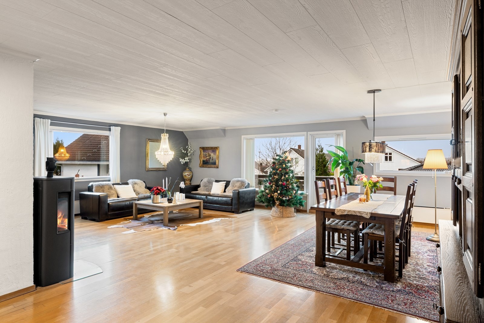 Stor og lys stue med parkett på gulv moderne peisovn og utgang til balkong. Her er det plass til både sofagruppe og spisebord. Galleribilde