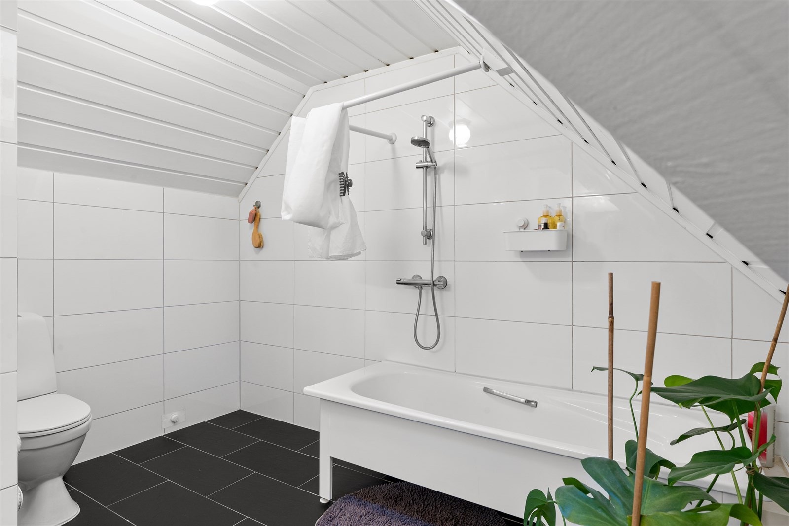 Pent bad med fliser på gulv og vegg, badekar, wc og vask. Galleribilde