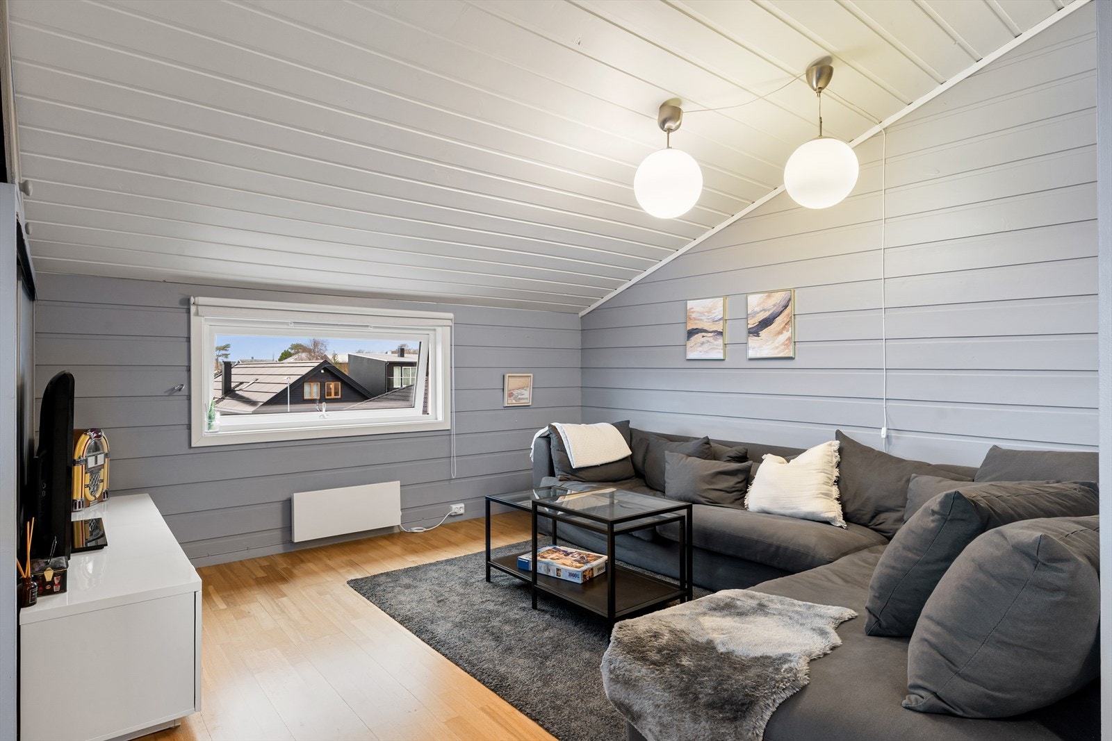 Kjekk loftstue med kontorplass. Parkett på gulv og malt panel på vegger og tak. Utsikt mot Stokkavannet fra sofakroken. Galleribilde