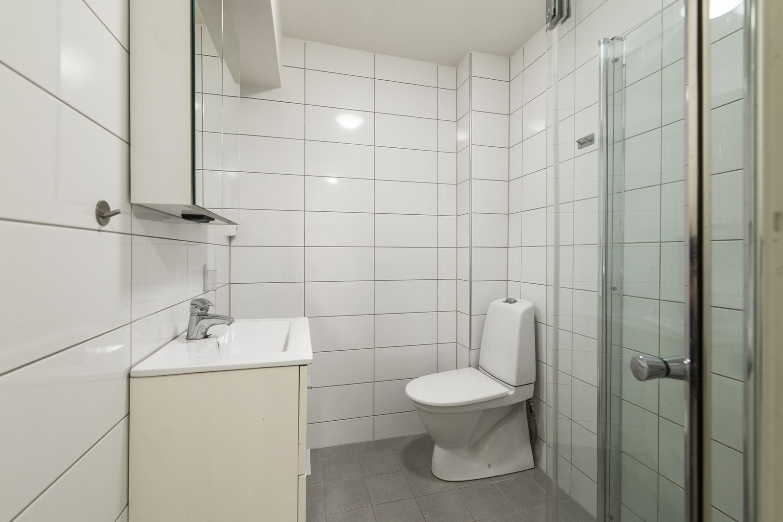 Tidsriktig lyst flislagt bad med dusjnisje og servant i innredning Galleribilde