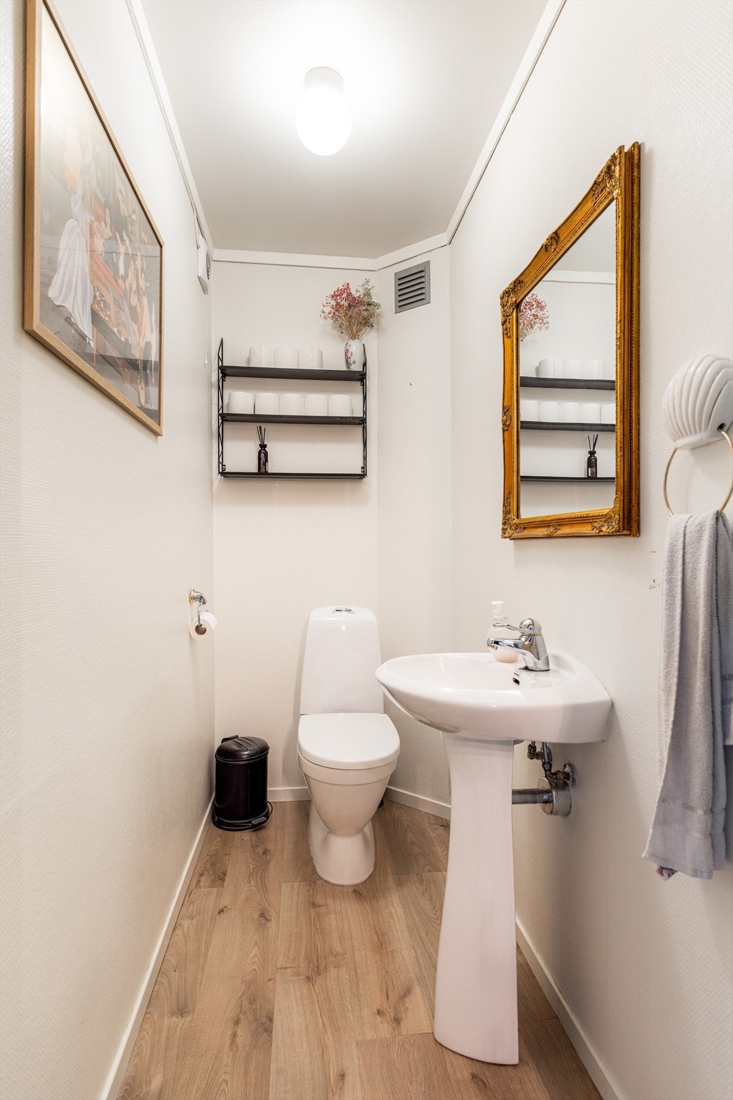 Leiligheten har eget toalettrom med moderne laminat på gulvet og lysmalte veggoverflater. Rommet er innredet med en elegant søylevask og nytt toalett. Elektrisk avtrekk. Galleribilde