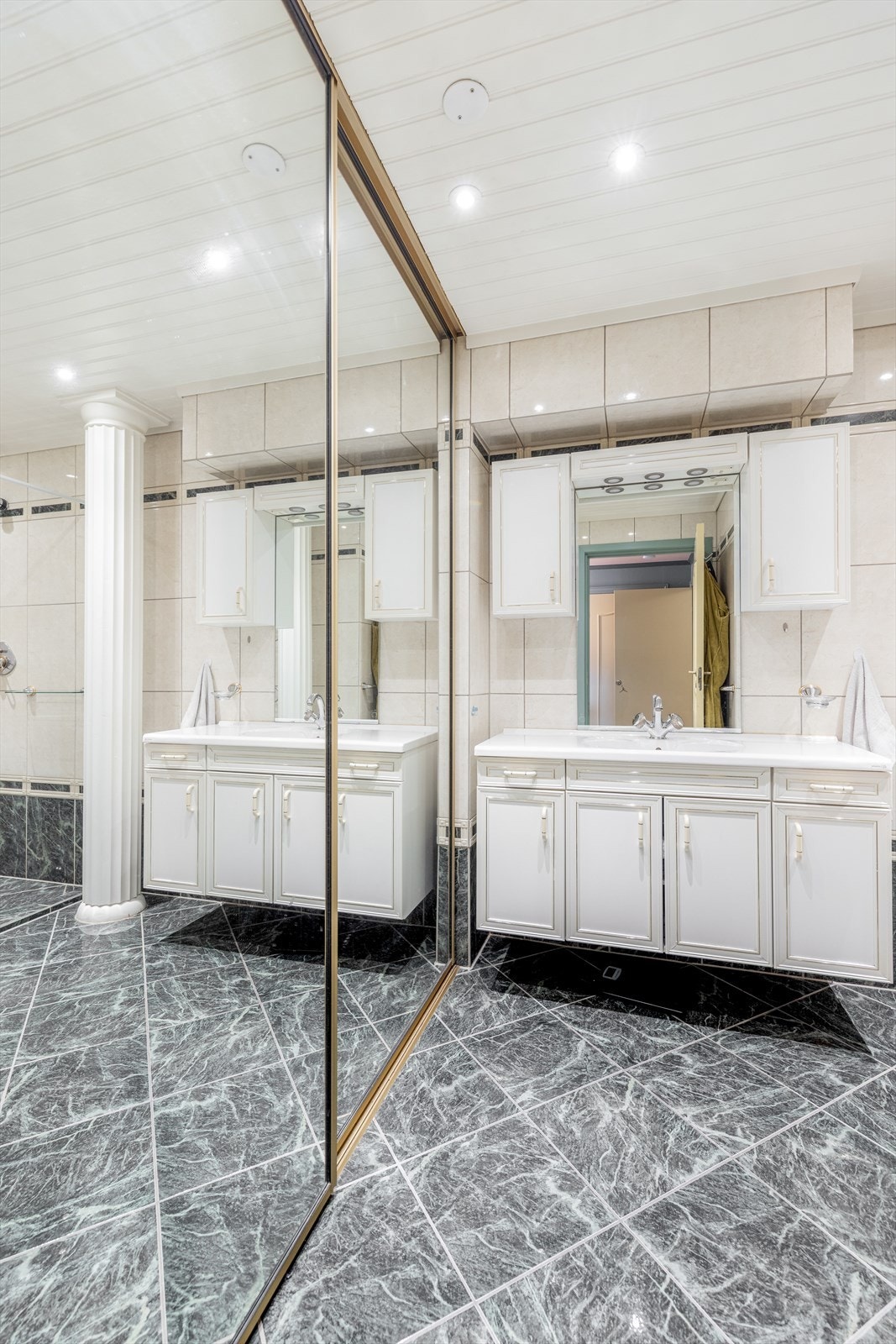 Flislagt baderom som har skyvedør til vaskenisje med plass til vaskemaskin og tørketrommel Galleribilde