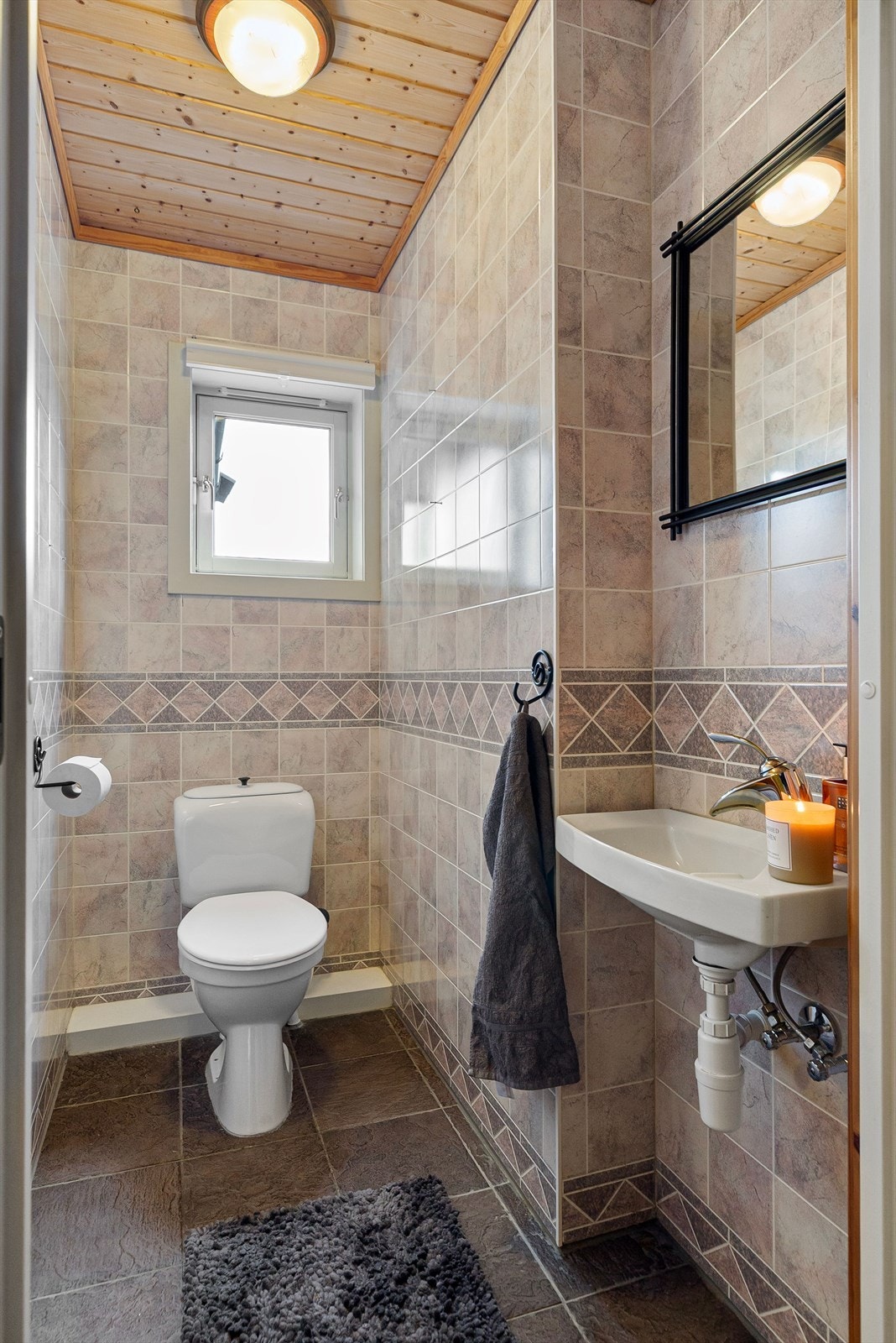 Vegg i vegg med vaskerommet nede finner man et separat wc-rom med våtromsplater. Galleribilde