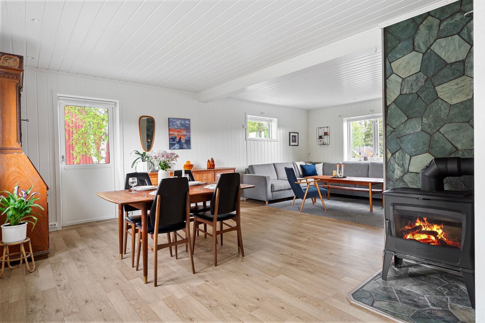 Atmosfæren i hovedstuen er lun og god, med både varmepumpe og en vedovn fra 2024. Galleribilde