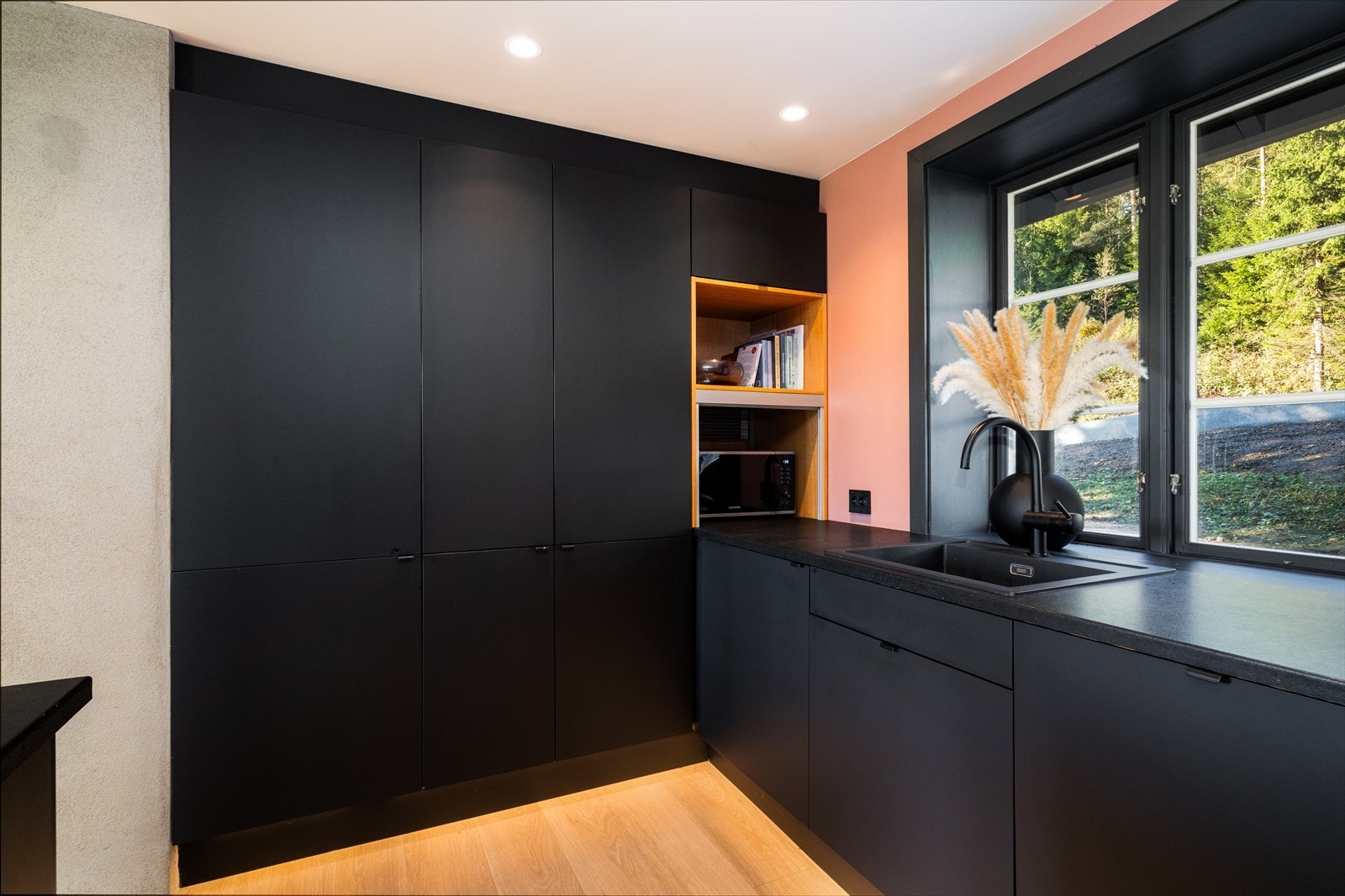 Innredningen på kjøkkenet består av mørke, slette fronter og laminert benkeplate med nedfelt vask i kompositt. Galleribilde