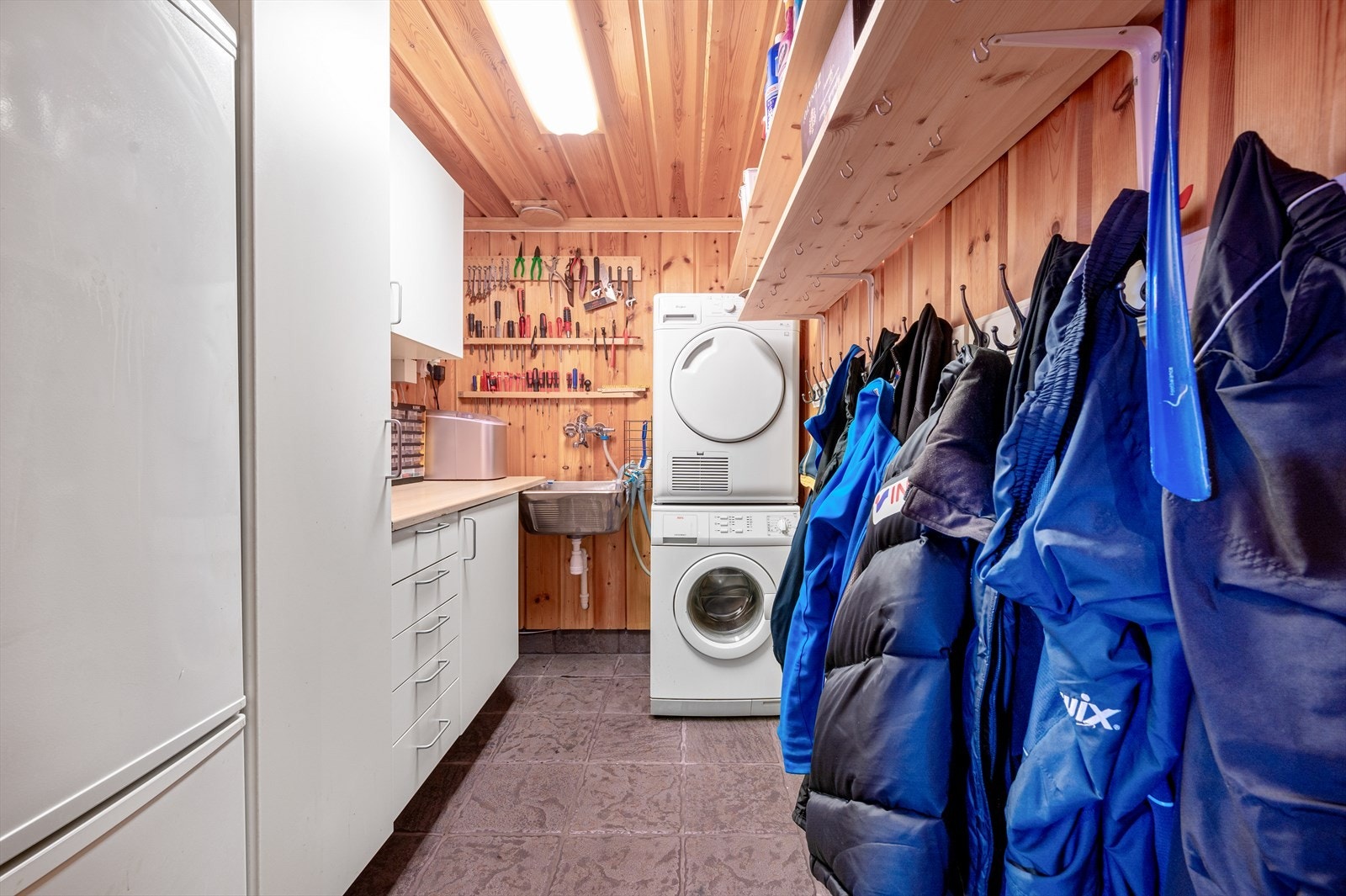Romslig vaskerom/bod bestående av garderobeskap, kjøle/fryser, vaskekum og opplegg for vaskemaskin og tørketrommel. Galleribilde