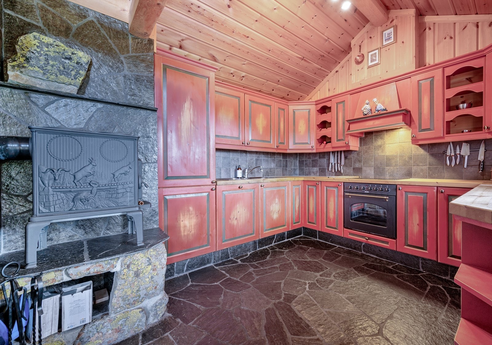 Flott kjøkken med profilerte fronter og fliser på bakvegg. Det er også plassert en vedovn på kjøkkenet for ekstra varme Galleribilde