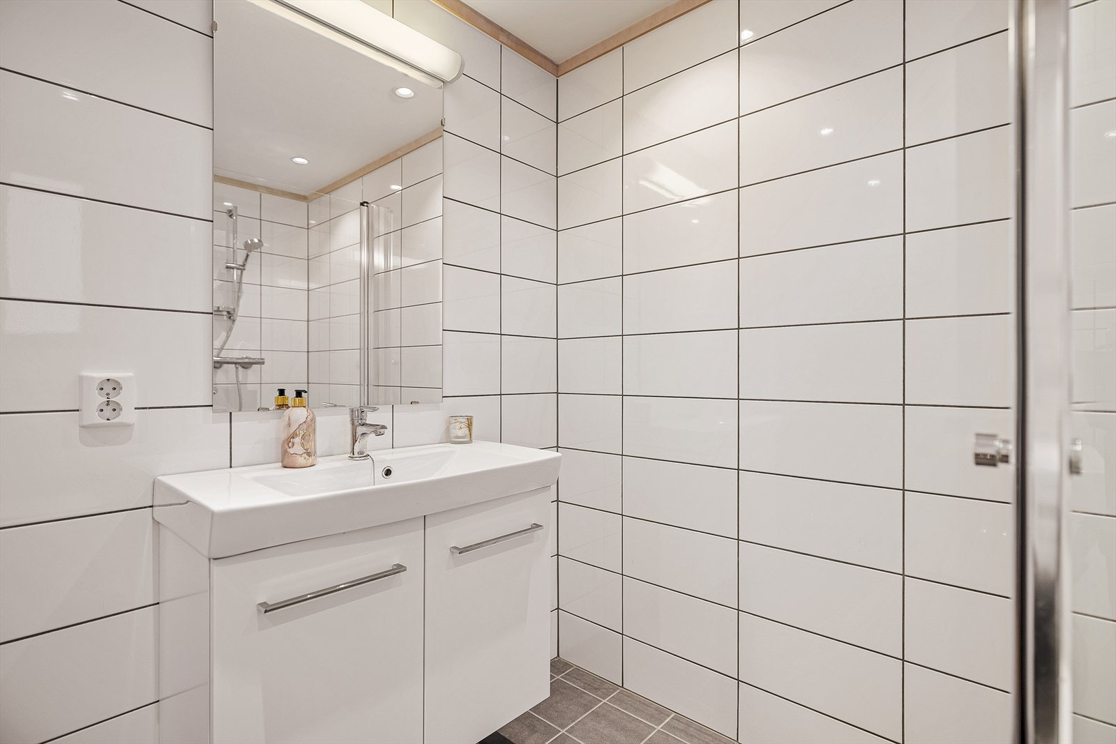 Badet er innredet med dusjhjørne, vegghengt toalett og servant Galleribilde