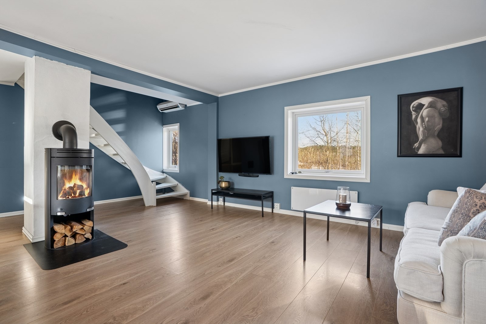 Stuen og kjøkkenet har klassisk enstavs parkett på gulvet, malte vegger og hvite plater i himlingen. Stemningsfull vedovn for ekstra hygge gjennom vinterhalvåret. Galleribilde