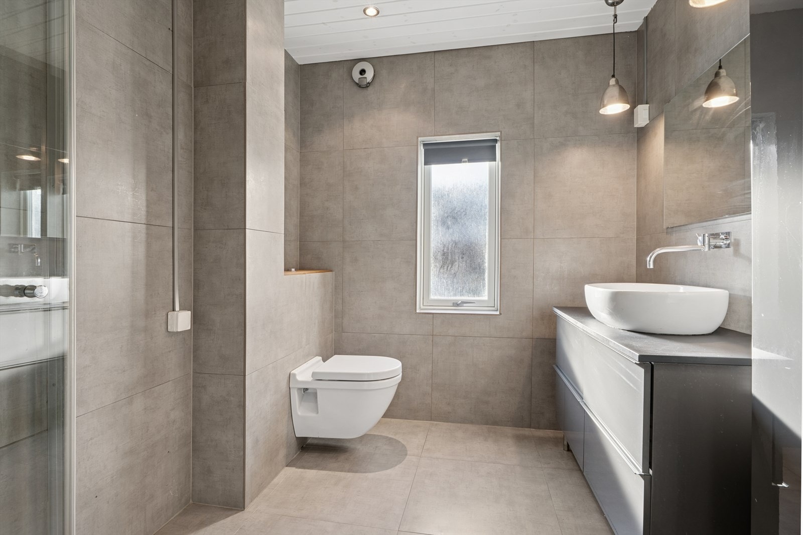 Flislagt bad med store moderne fliser i en dus og delikat beige farge. Galleribilde