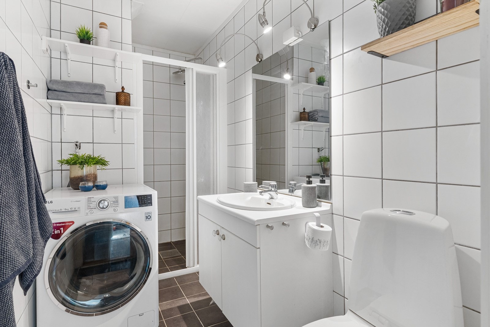 Badet er flislagt og utstyrt med dusjløsning, servant med innredning og toalett. Galleribilde