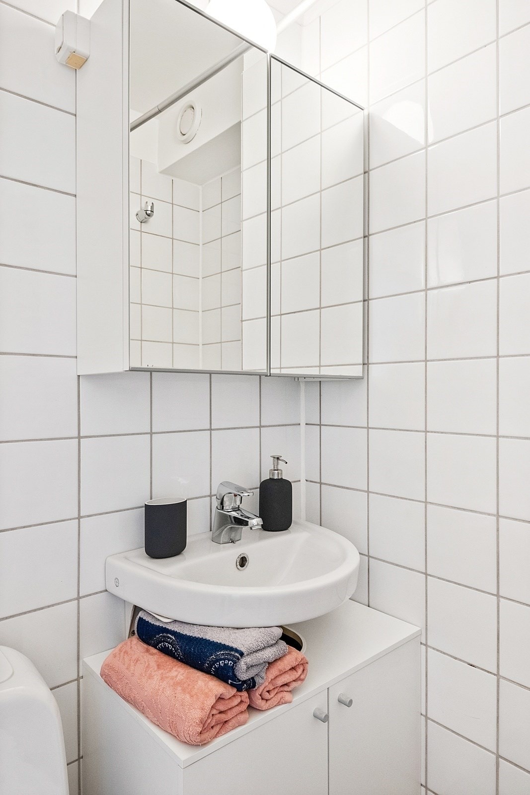 Badet er innredet med gulvstående toalett, vegghengt servant og servantskap med slette fronter. Det er vegghengt speilskap og stikkontakt over servant. Galleribilde