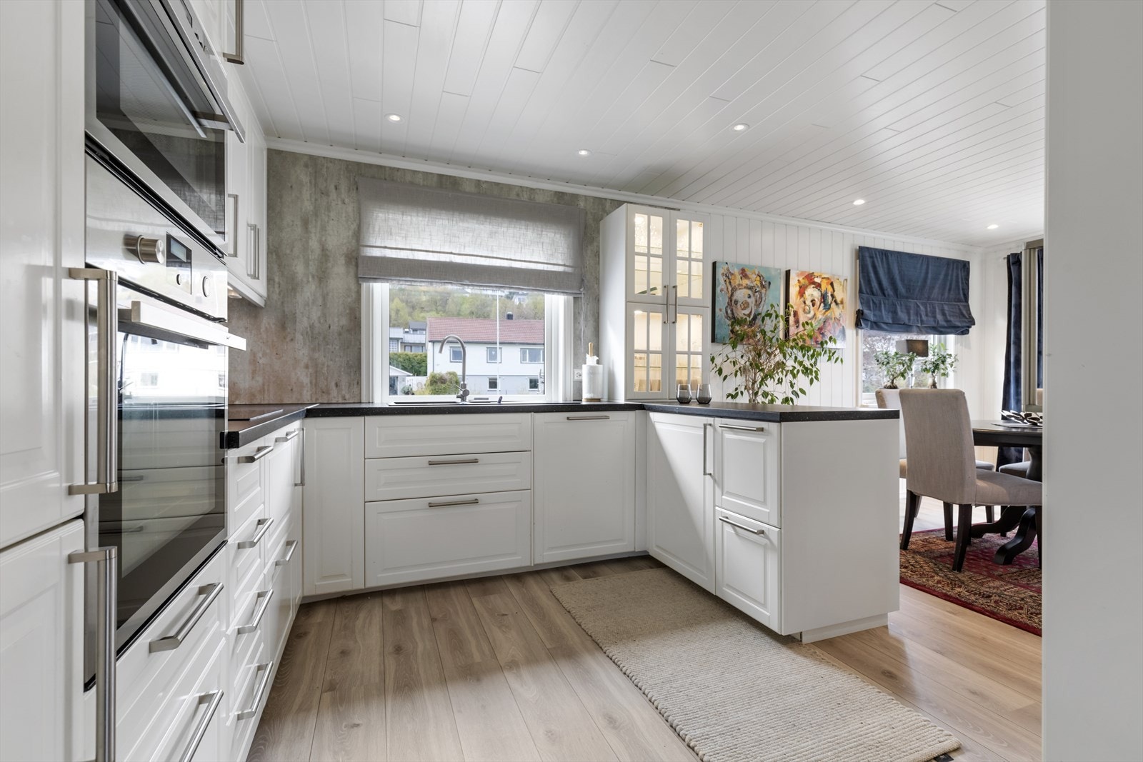 Kjøkken i hovedetasjen har profilerte, malte skapfronter og med glass med takhøye skap | benkeplater av laminat med nedfelt vask og platetopp | integrert mikroovn, komfyr, ventilator, oppvaskmaskin og kjøle-/fryseskap Galleribilde