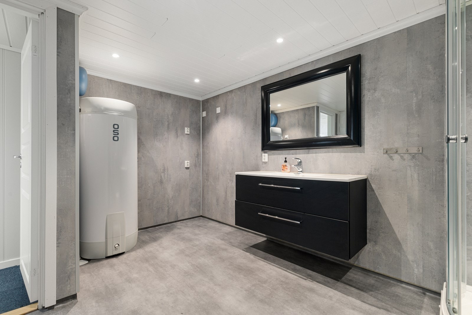 Bad/vaskerom i kjelleretasjen har vinylbelegg på gulv og våtromsplater på vegger | rommet er utstyrt med baderomsinnredning, wc, dusjvegger og opplegg for vaskemaskin og tørketrommel Galleribilde