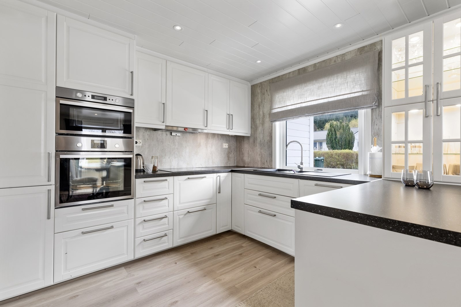 Kjøkken i hovedetasjen har profilerte, malte skapfronter og med glass med takhøye skap | benkeplater av laminat med nedfelt vask og platetopp | integrert mikroovn, komfyr, ventilator, oppvaskmaskin og kjøle-/fryseskap Galleribilde