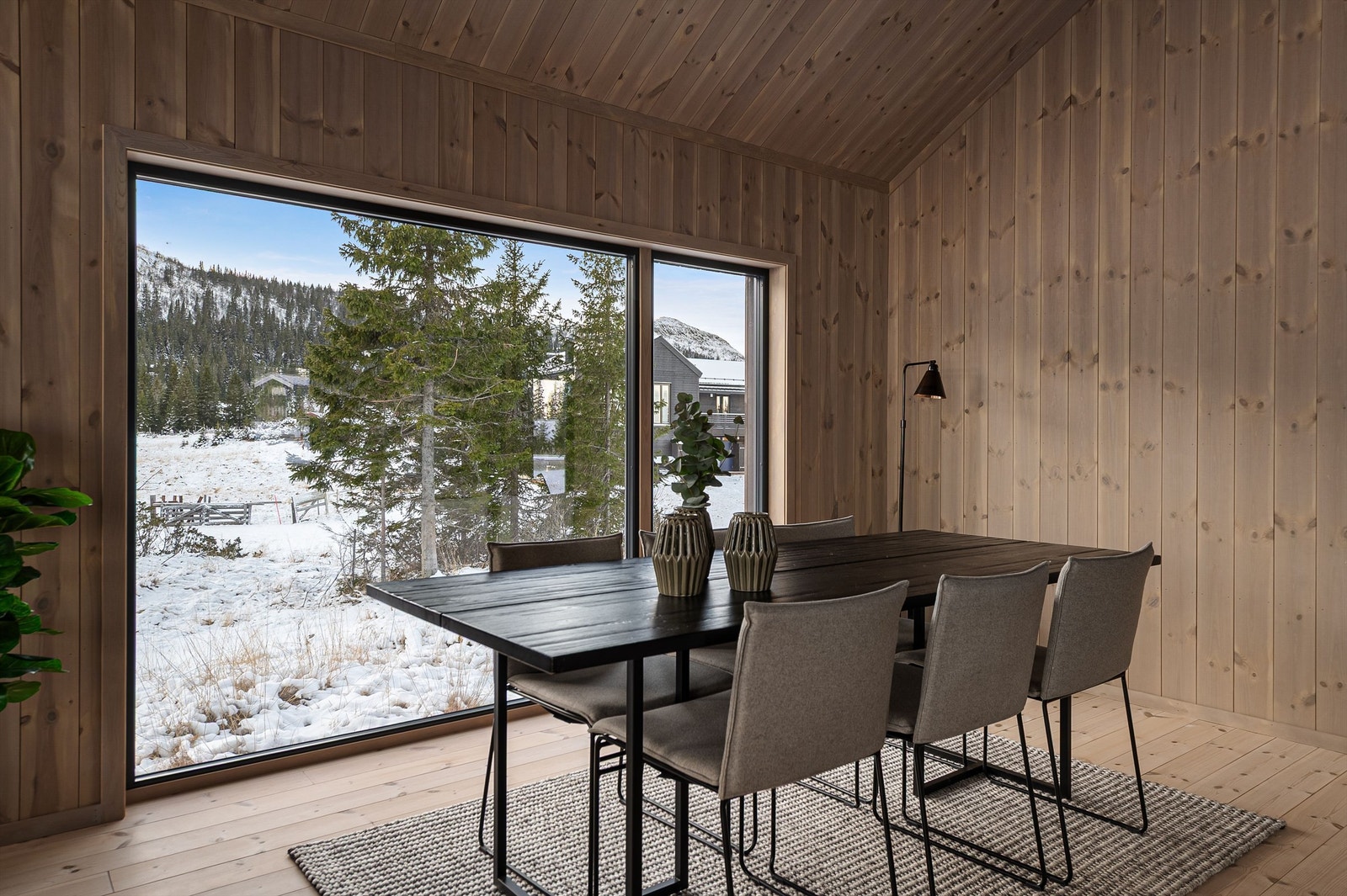 Spisestuen er rammet inn av et stort vindu som bringer naturen inn. Galleribilde