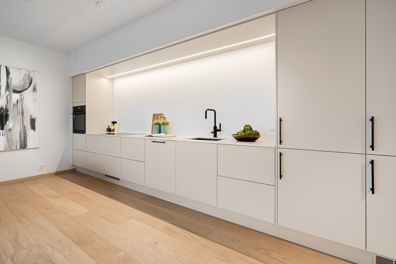 Integrerte hvitevarer som kjøleskap med frys, stekeovn, oppvaskmaskin og koketopp med ventilator. Det er god benke- og skapplass. Galleribilde