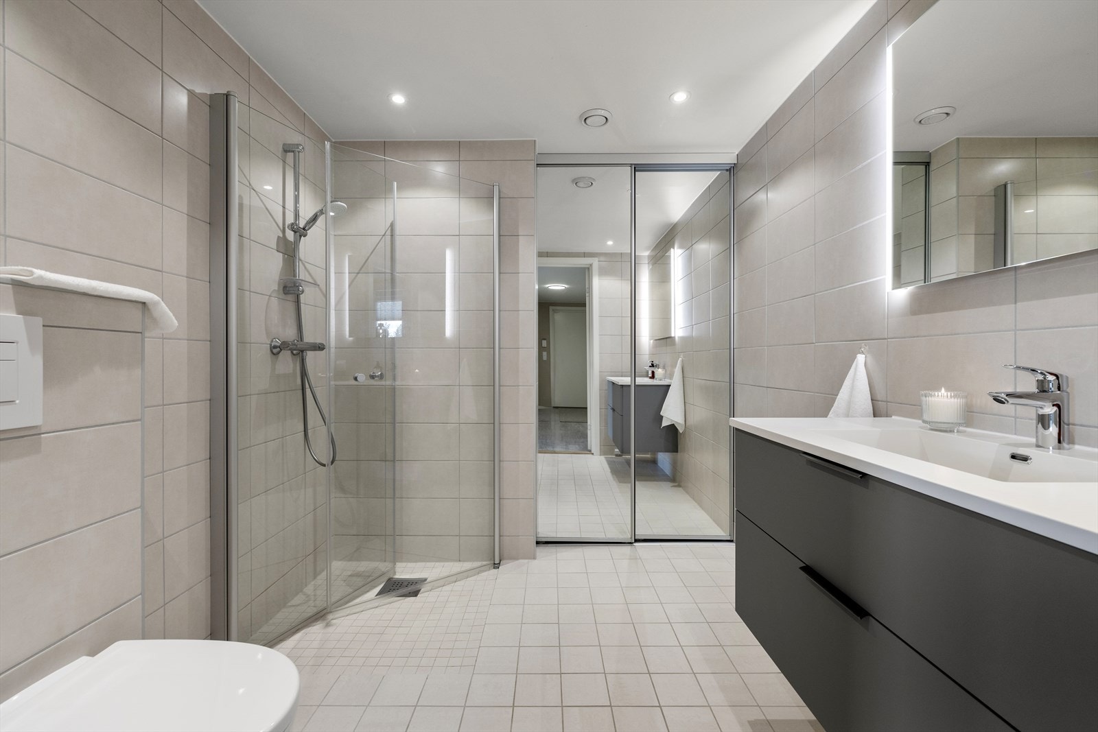 Badet er utstyrt med vegghengt toalett, dusjnisje, baderomsinnredning med servant og speilskap. Galleribilde