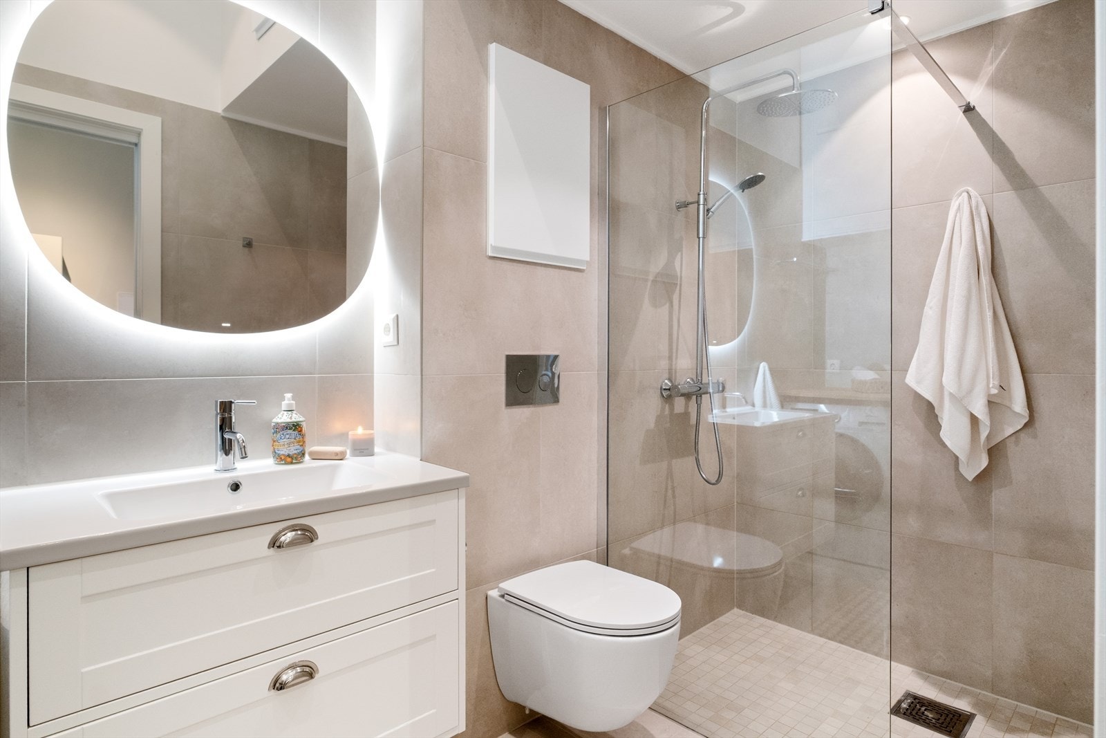 Et påkostet bad i tidløs og moderne stiil. 60x60 fliser på vegger og gulv. Egen flott dussjone, vegghengt toalett og servant med underskap og speil Galleribilde