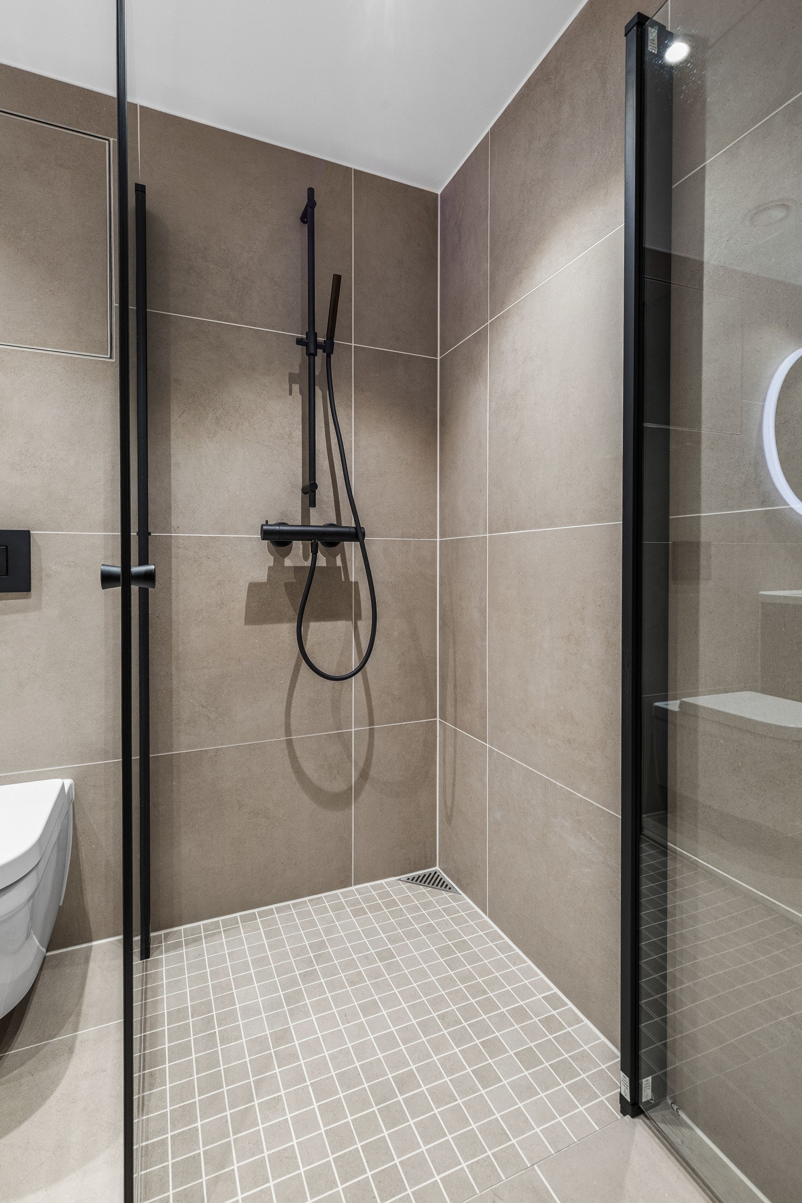 Flisene i grå-beige toner skaper en rolig og stilren atmosfære. Galleribilde