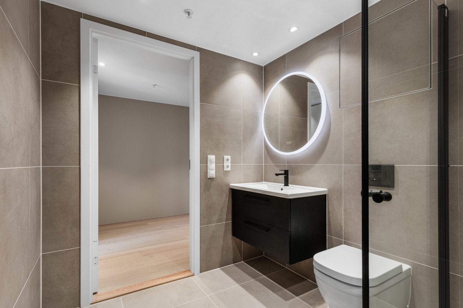 Badet er lekkert innredet med sort baderomsmøbel med store skuffer, og sort garnityr. Galleribilde