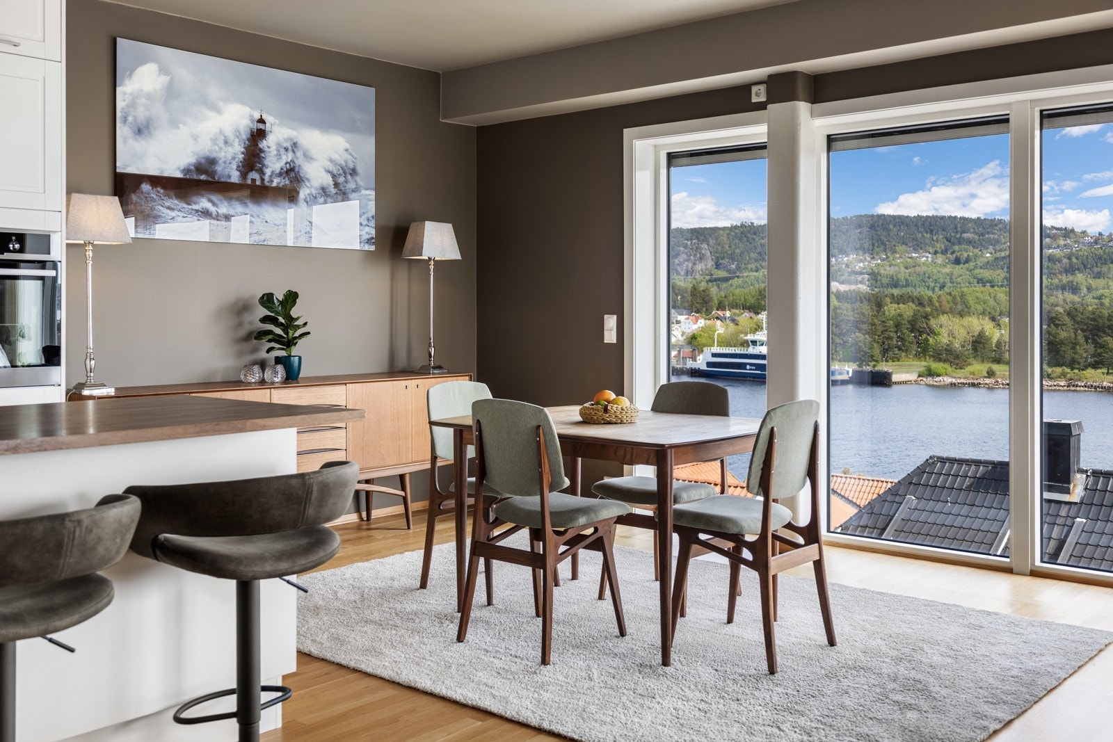 Lyst og romslig oppholdsrom med store vinduer og flott utsikt over fjorden og omkringliggende natur. Galleribilde