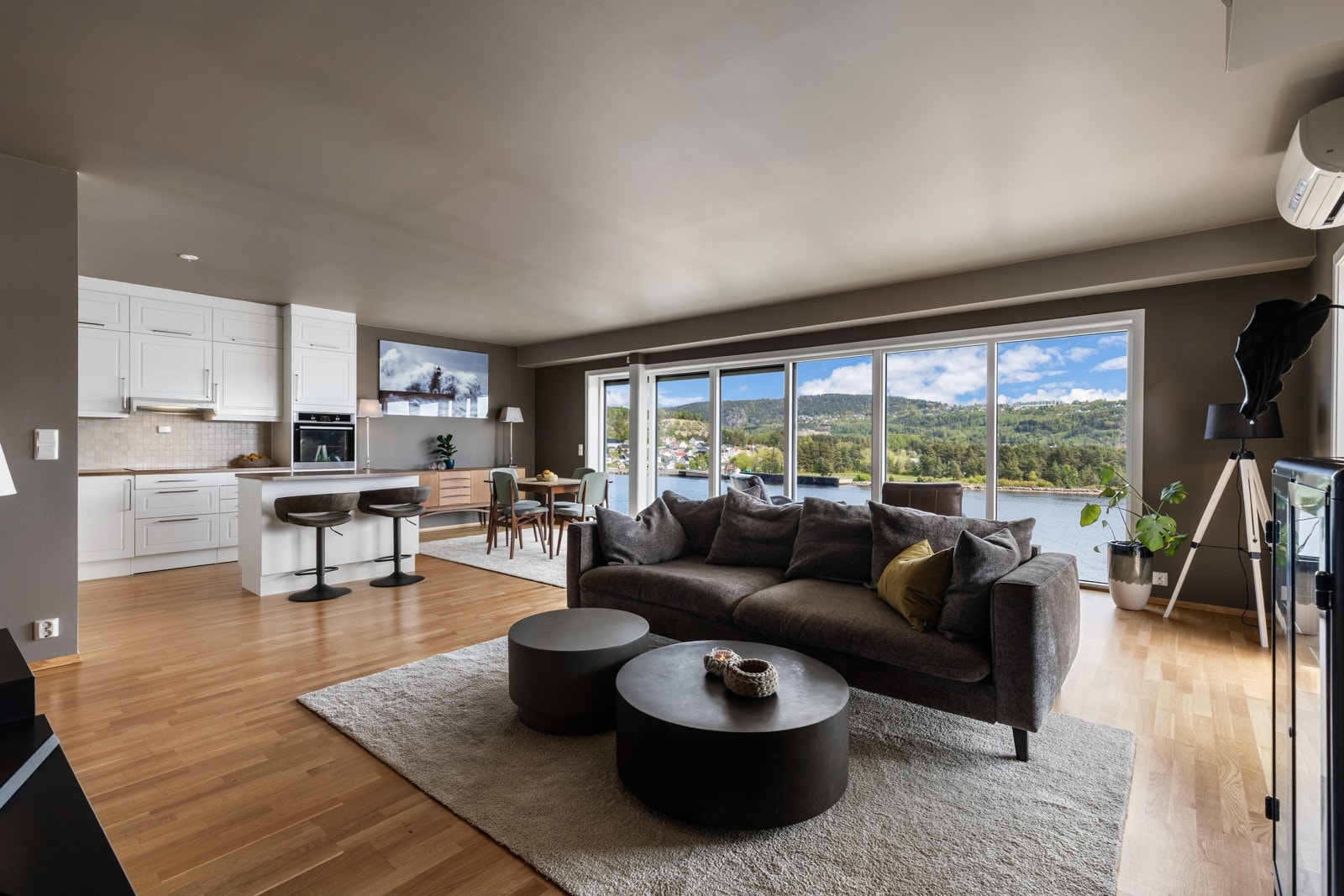 Lys og romslig stue med åpen kjøkkenløsning og store vindusflater som gir flott utsikt mot naturen. Galleribilde