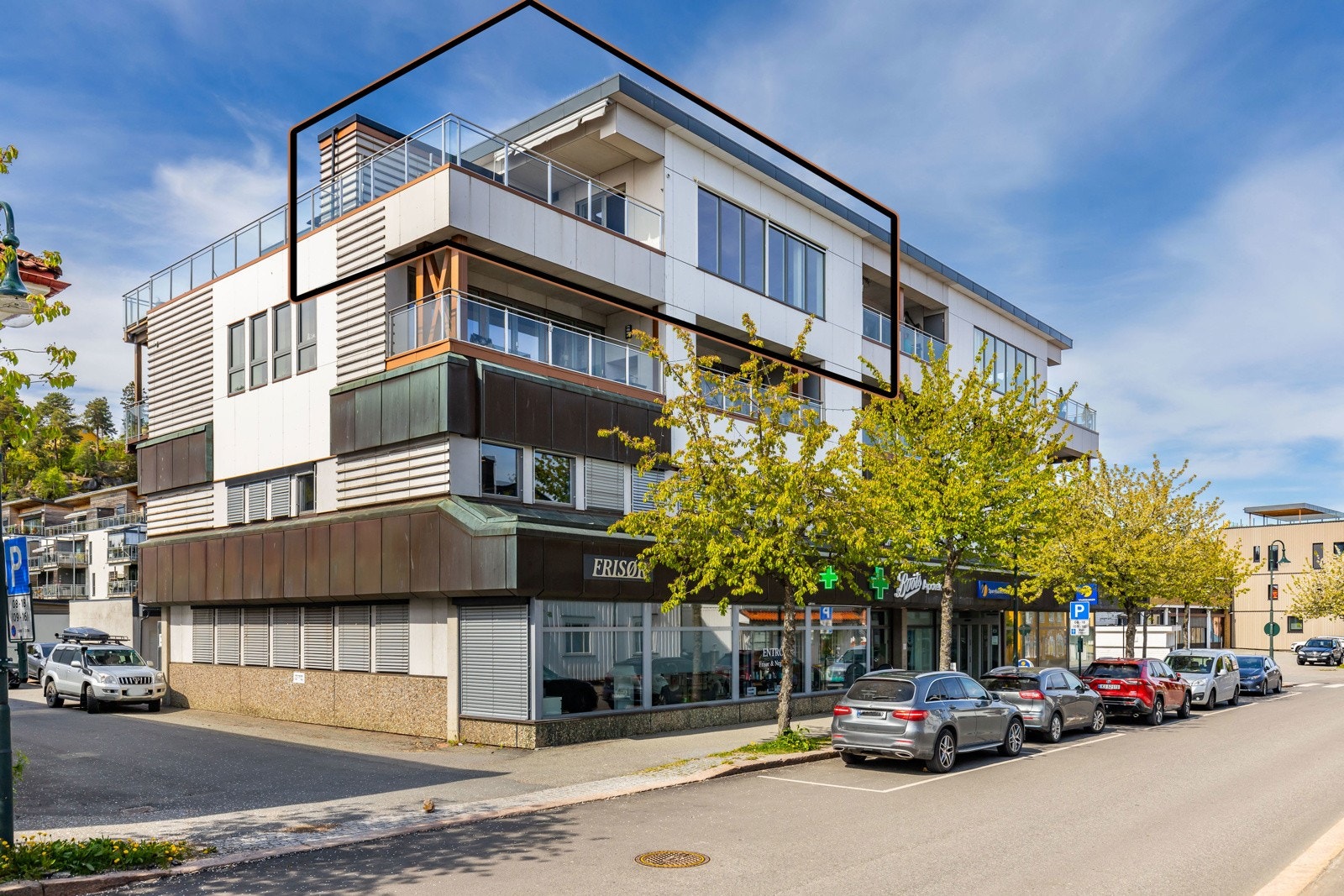 Moderne bygård med næringslokaler i første etasje og leiligheter med balkonger i de øvre etasjene. Galleribilde