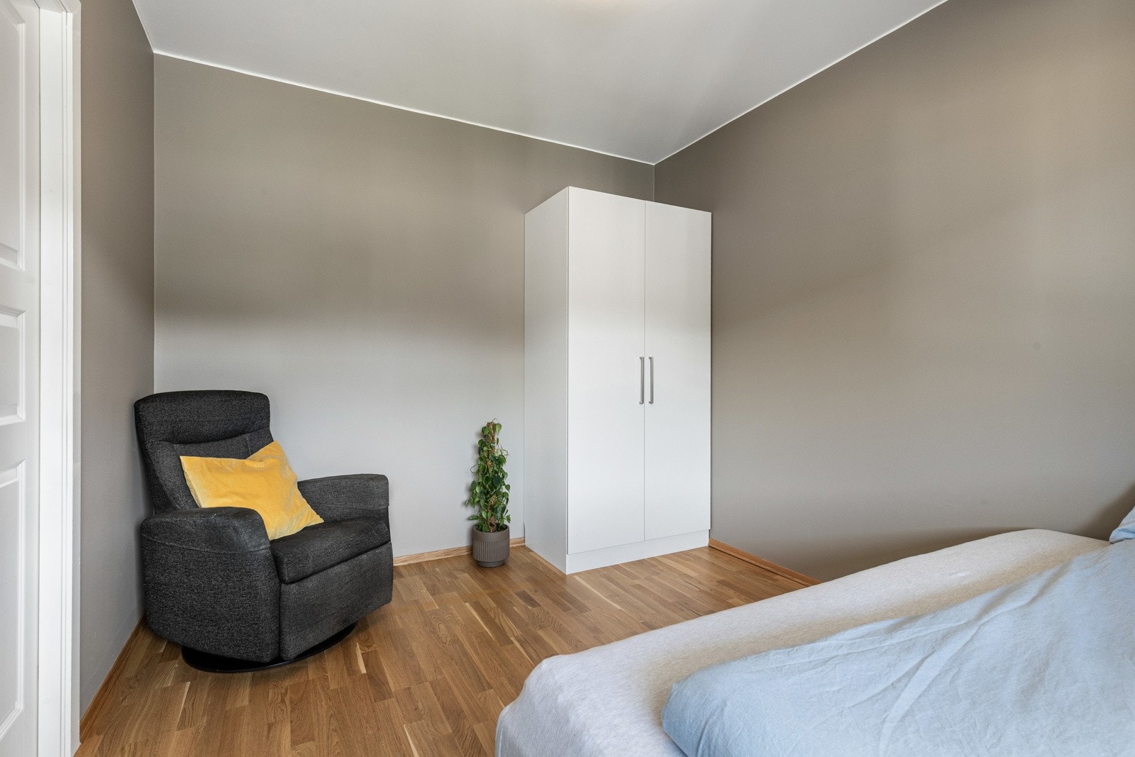 Lyst soverom med grå vegger, parkettgulv og garderobeskap. Galleribilde