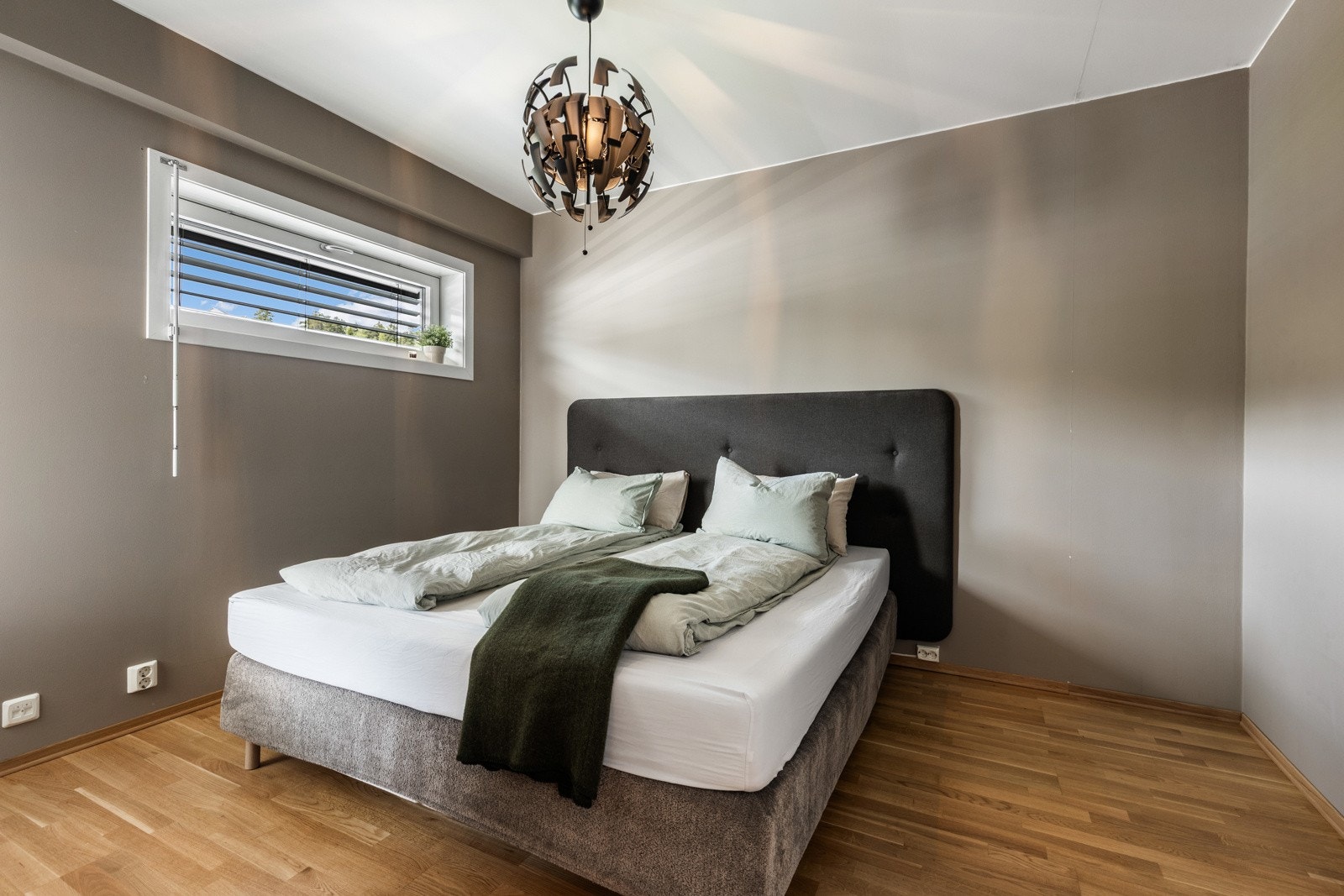 Lyst soverom med dobbeltseng, parkettgulv og et stort vindu som slipper inn naturlig lys. Galleribilde