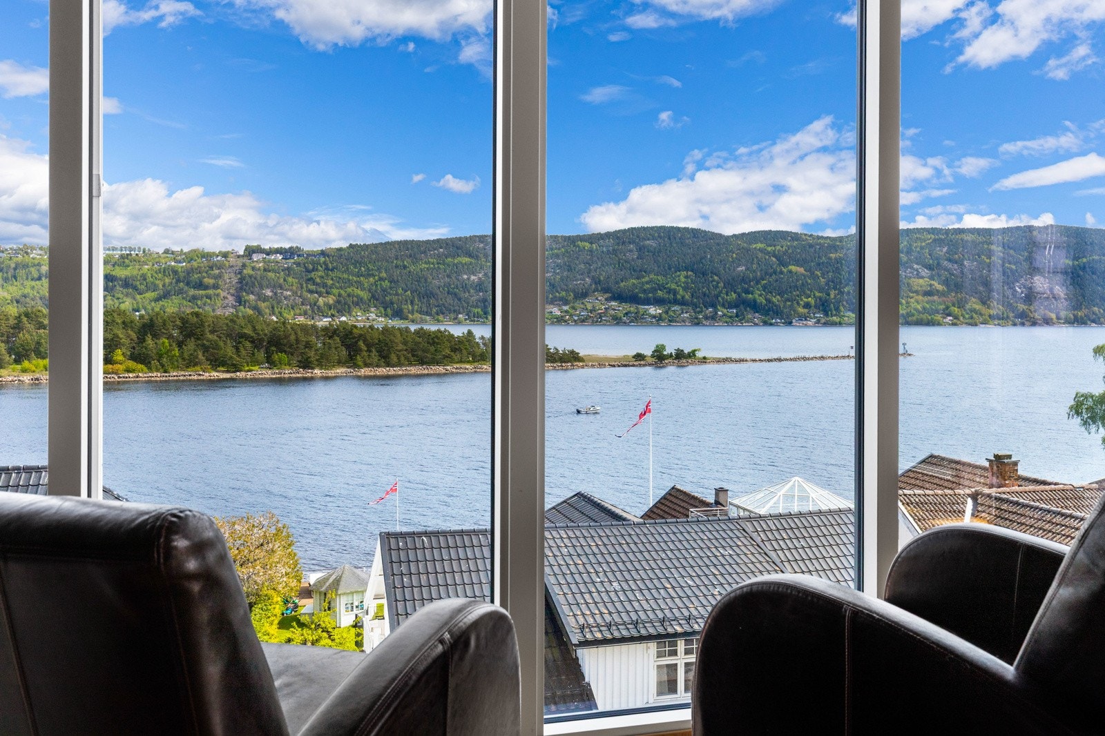 Store vinduer med utsikt over vannet og åsene i bakgrunnen. Lys og luftig atmosfære. Galleribilde