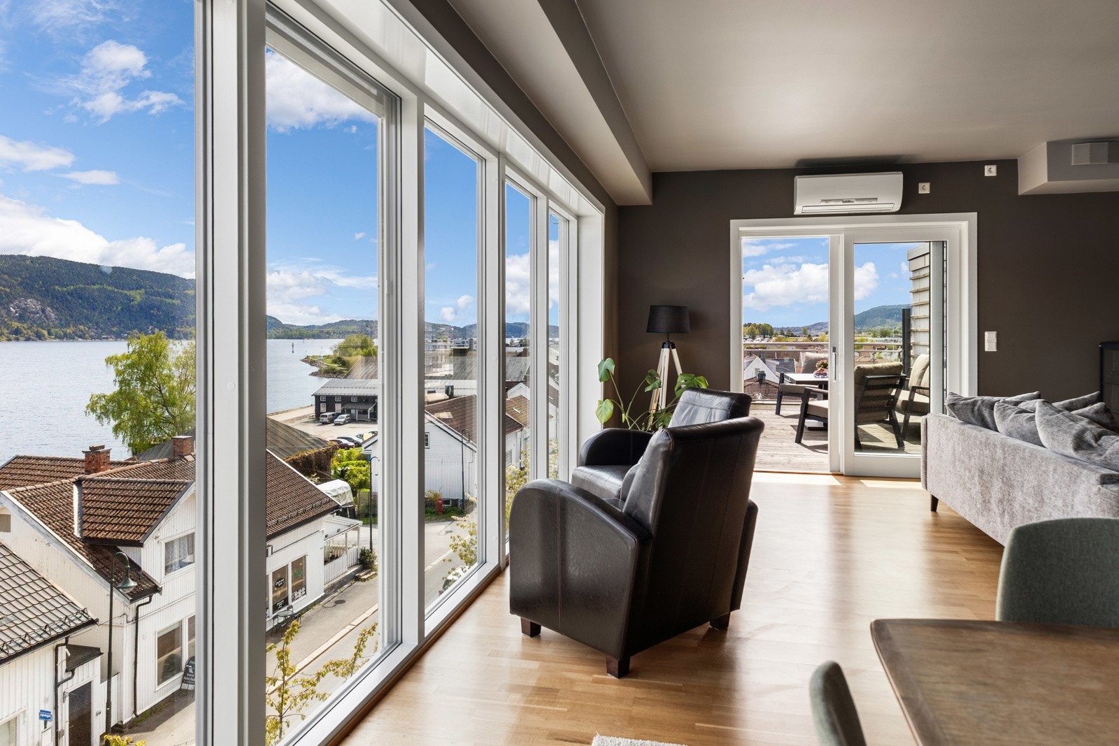 Romslig stue med store vinduer som gir flott utsikt over vannet og tilgang til en balkong. Galleribilde