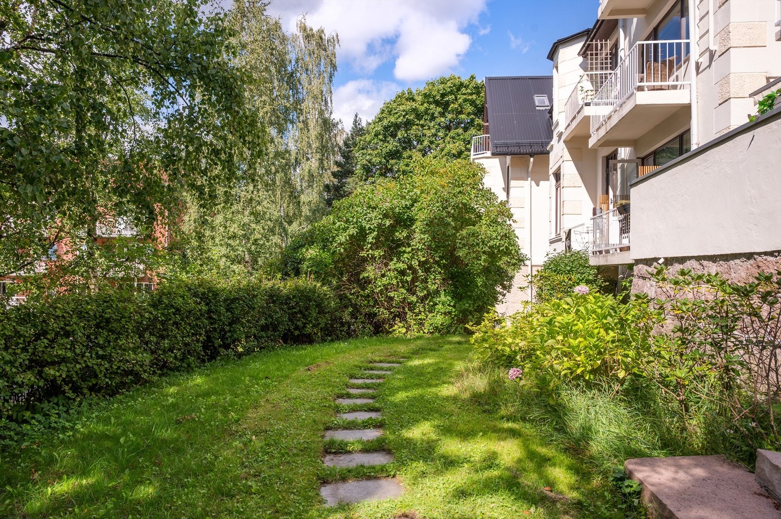 Stor, felles hage som er pent opparbeidet med gangstier, gressplen og beplantning. Galleribilde