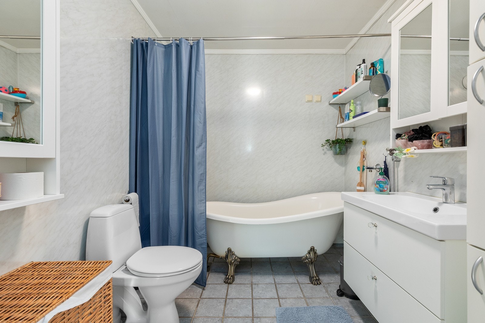 Badet har flisar på golv og baderomsplater på veggar. Badet er utstyrt med toalett, badekar, dusjforheng, innreiing med skuffer, sideskap og overskap. Galleribilde