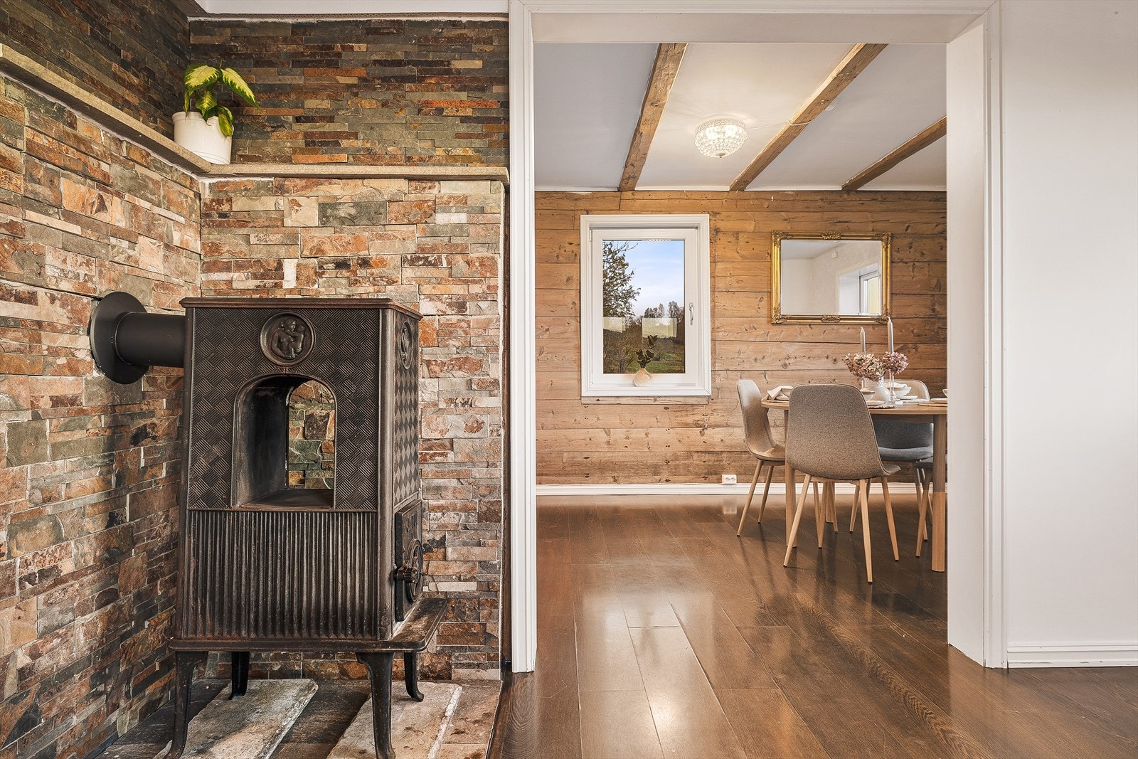 Overgangen fra kjøkken til spisestue blir møtt med en antikk vedovn, som varmer rommene godt opp ved kalde høst- og vinterdager Galleribilde