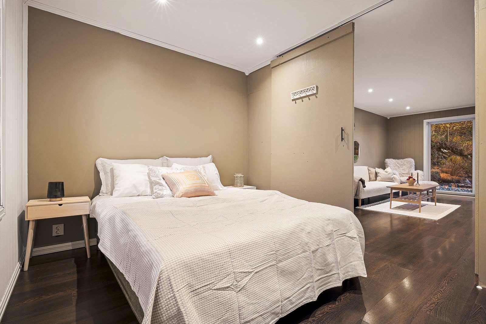 Boligens første soverom møter oss ved stuen. soveværelset er utstyrt med en fin skyvedør som gjør det sømløst å adskille rommene. Det gjøres oppmerksom om at bildet som viser disse to rommene er en del av et tilbygg. Galleribilde