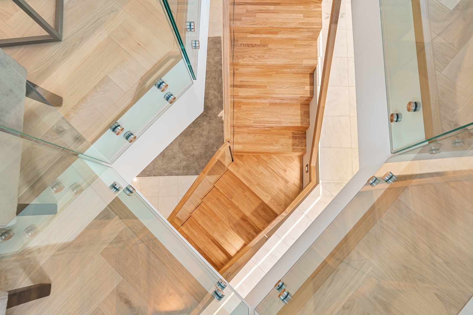 Trappen har trinn- og håndløpere i tre, glassfelt på én side samt belysning i form av dekorative vegglys og LED-lyslist. Galleribilde