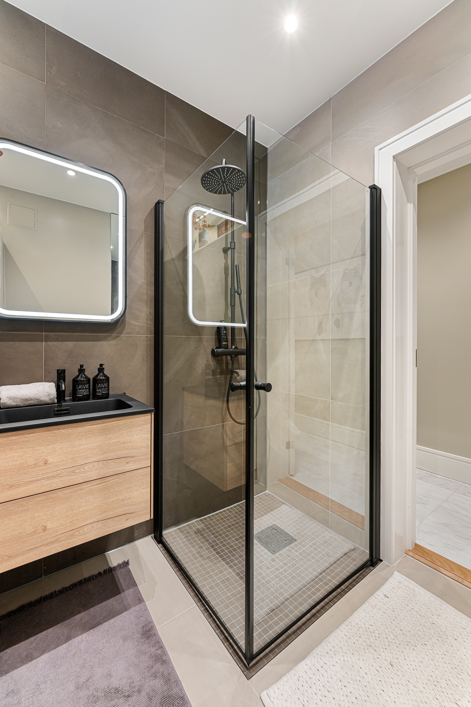 Romslig dusjnisje med regnfallsdusj og håndholdt dusj samt veggmontert klosett. Galleribilde