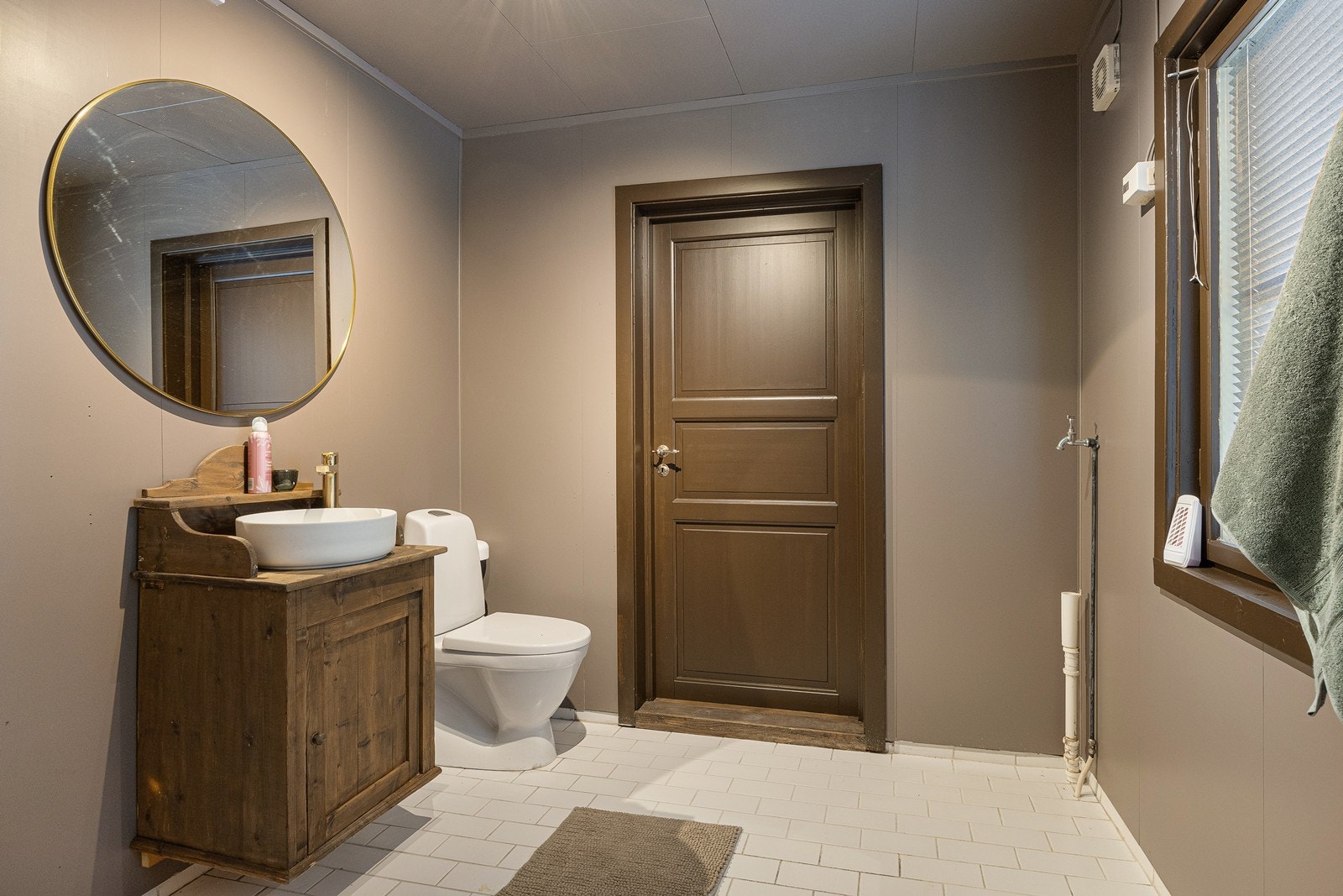 All innredning på badet i 1. etasje er oppgradert i 2025. Hvite gulvfliser kombineres med våtromsplater malt i en fin jordtone. Galleribilde