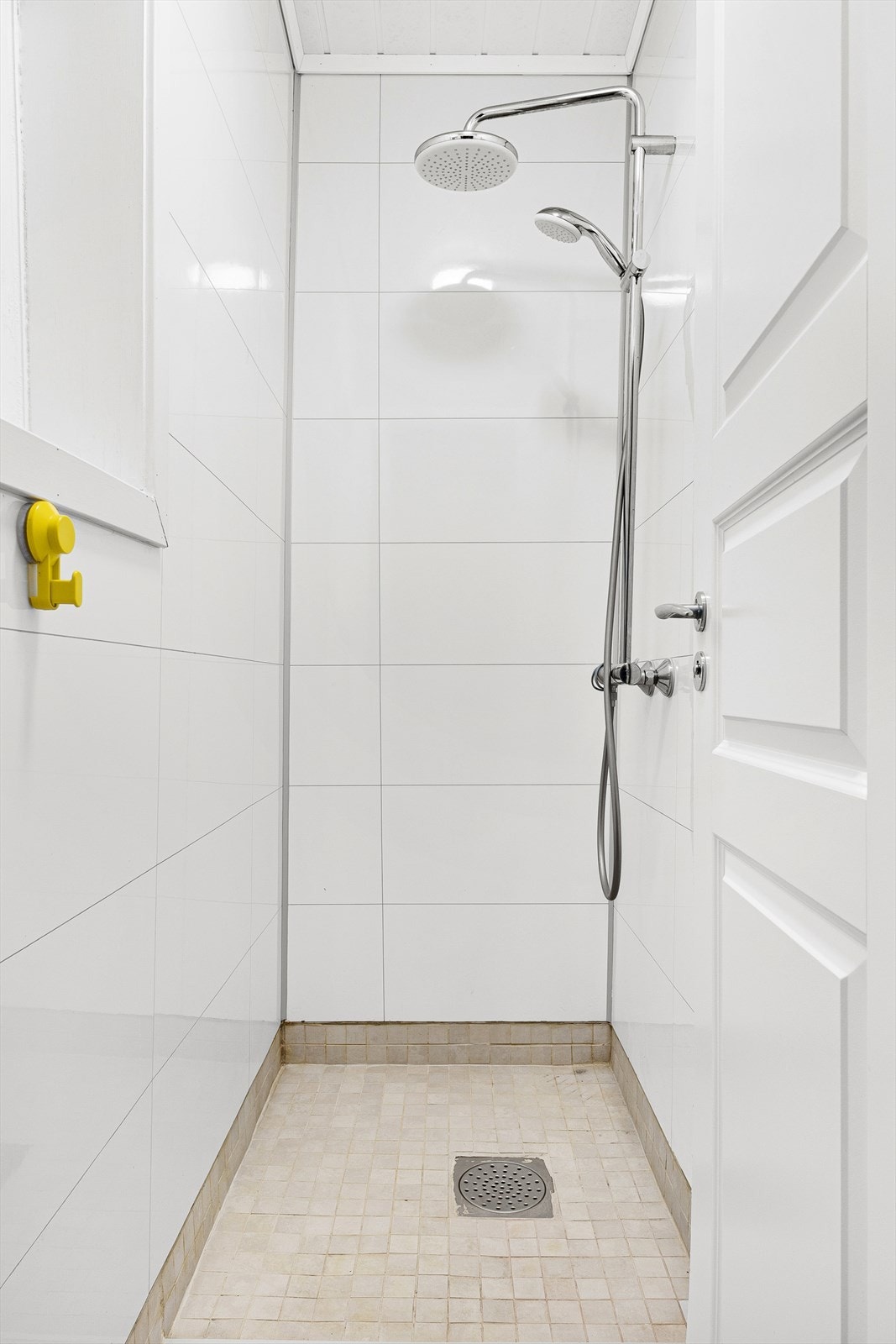 Det er innredet med fliser på gulv, baderomsplater på vegger og dusjgarnityr. Galleribilde