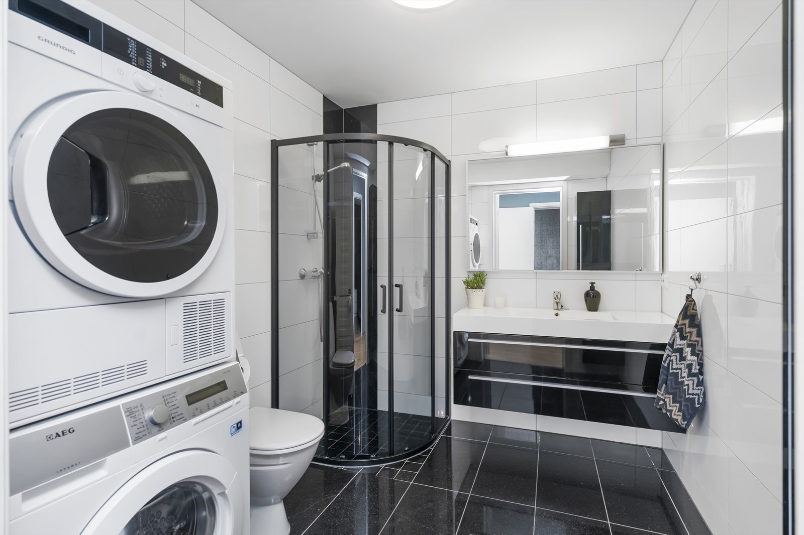 Flislagt bad/vaskerom med varmekabler i gulv. Baderomsinnredning, toalett og dusjhjørne. Galleribilde