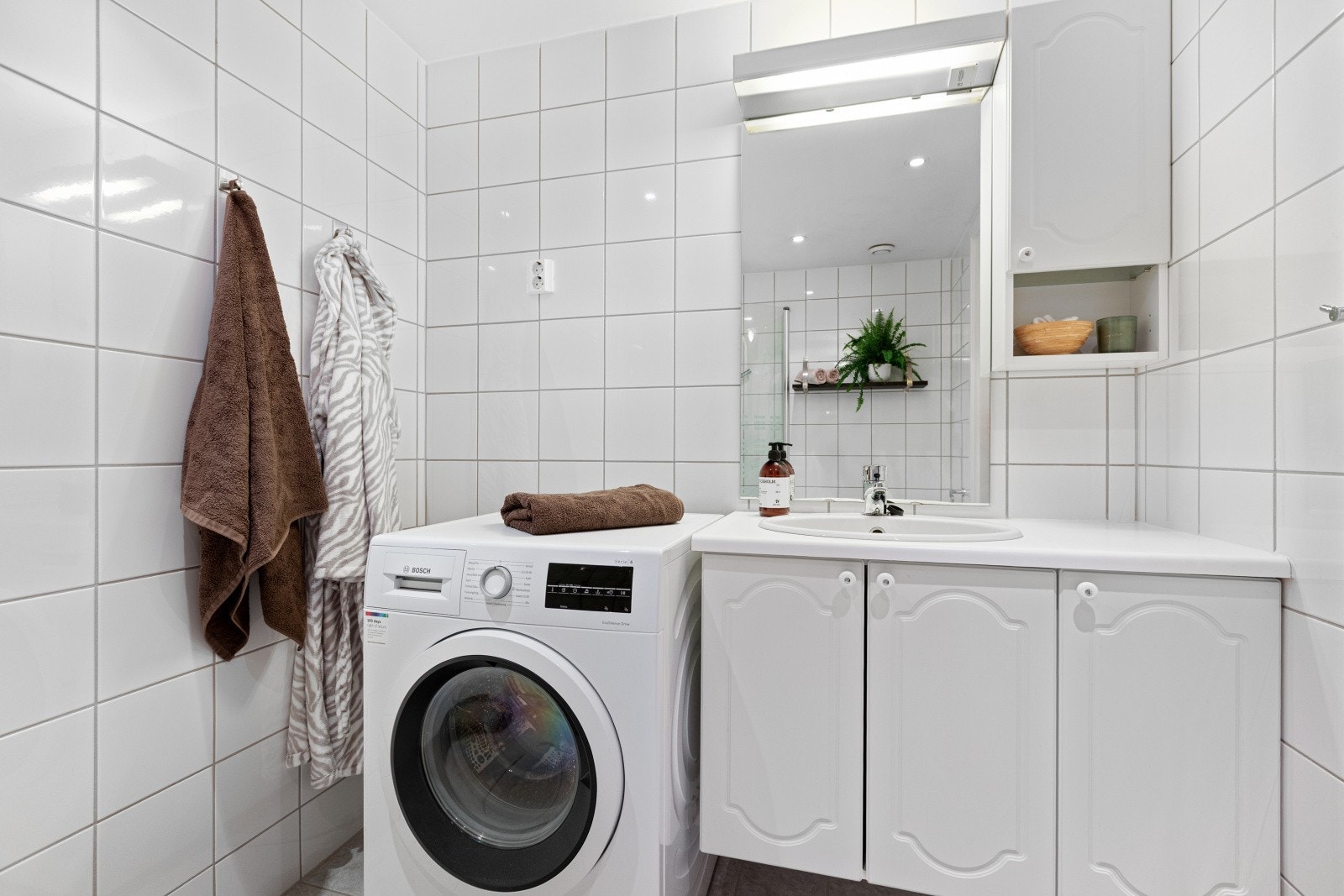 Rommet er innredet med servant med profilerte fronter, gulvstående toalett og dusjhjørne med to svingbare glassdører. Galleribilde