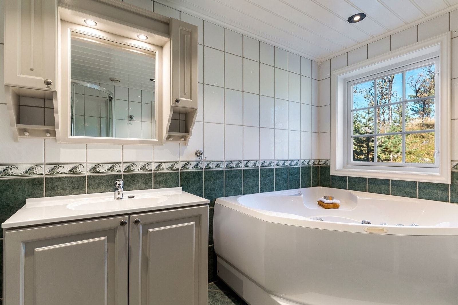 Romslig bad med boblebad, dusjhjørne og flislagte overflater. Galleribilde