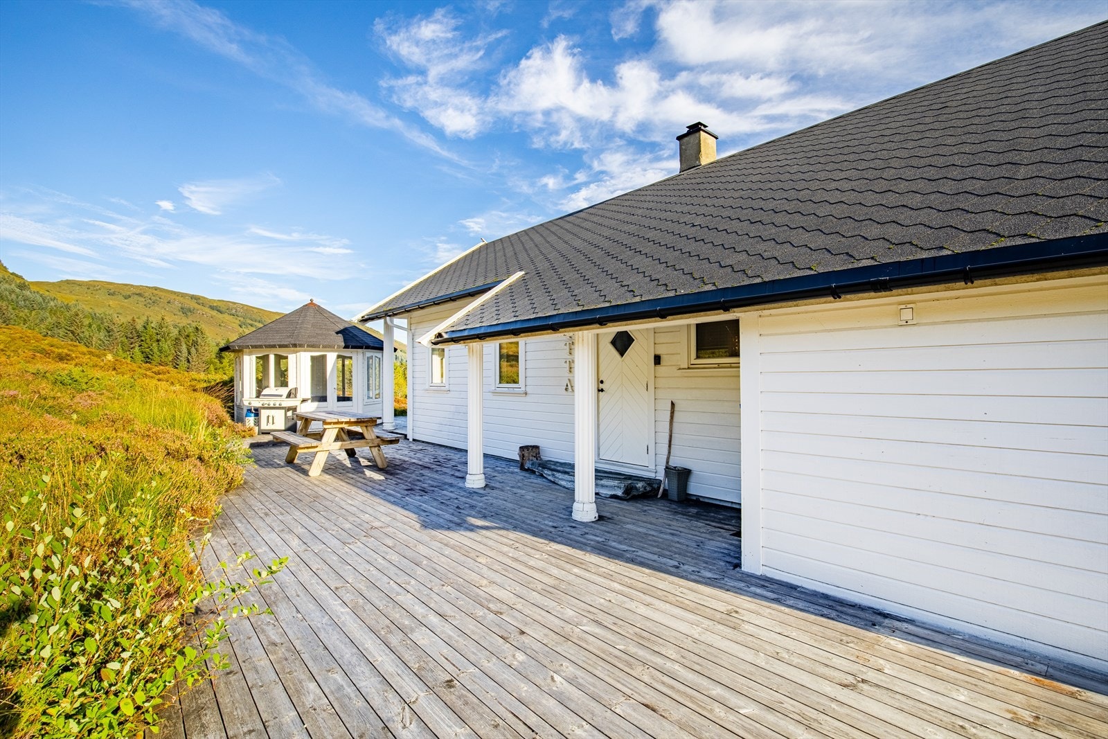 Stor terrasse som strekker seg rundt hjørnet på huset Galleribilde