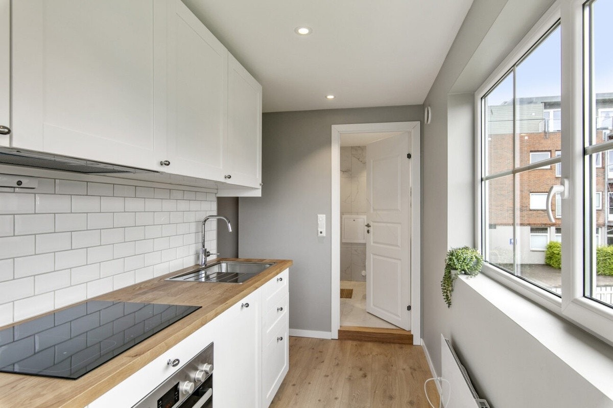 Kjøkkenet er lyst og innbydende med felles bad i enden Galleribilde